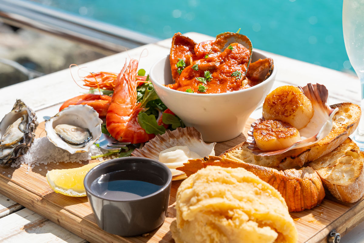 3 dishes and 2 glasses of wine on a table with an ocean view